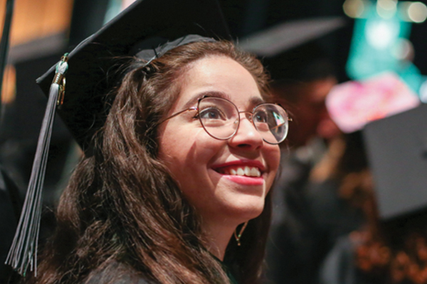 A woman smiling while wearing a graduation cap and gown