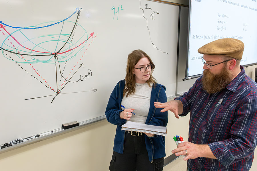 Caitlyn Hendricks asks a question after class about the 3 dimensional Minkowski space as Professor Mark Norfleet helps clarify.
