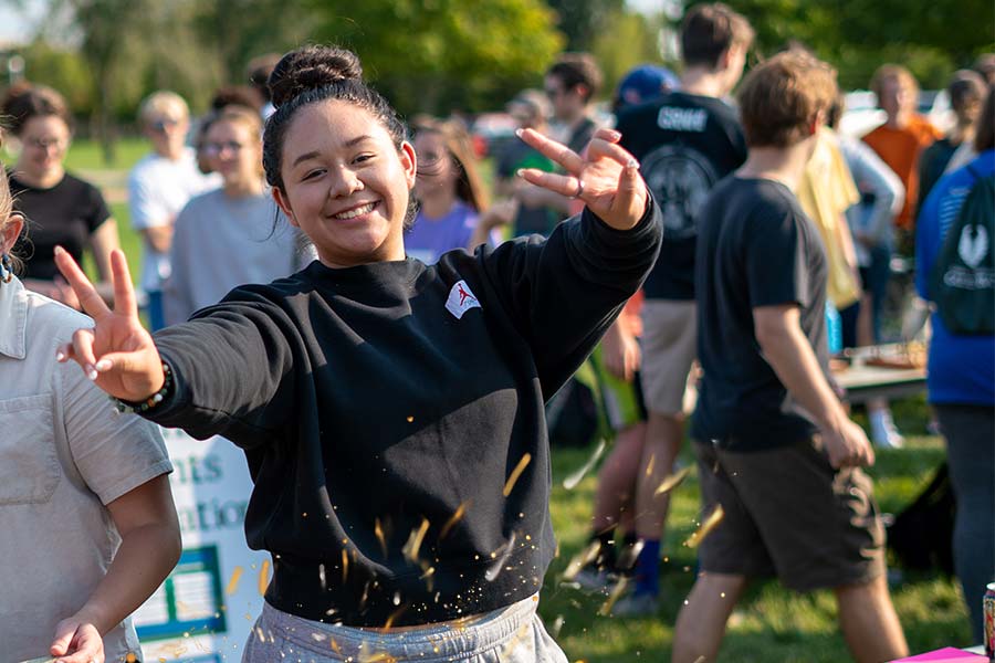 Student at GB Orientation, making the peace sign with her hands, sparks overlayed