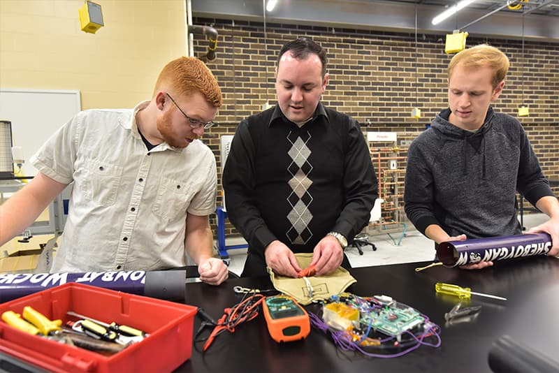 UWGB students and a professor work on a rocket for the student org Wombat Wockets.