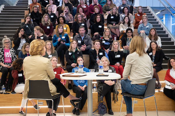 Two women leading a discussion with a bleacher full of people