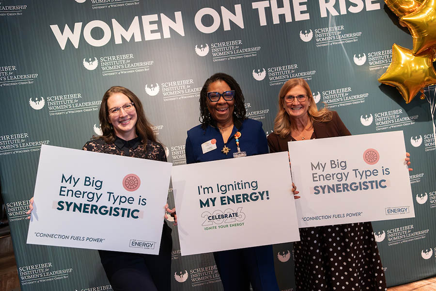 Three women posing with signs at the Celebrate 2026 event