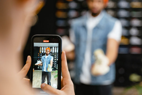 Entreprenuer takes photo of man holding shoes to promote his products