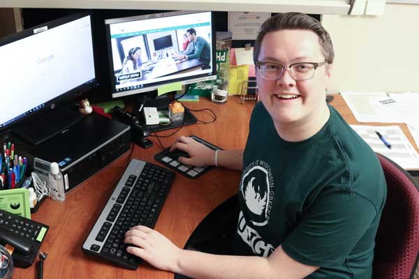 Male student smiles at camera while working on campus