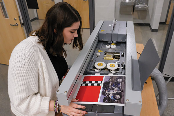 Samantha Myers using a press printer for a novel.