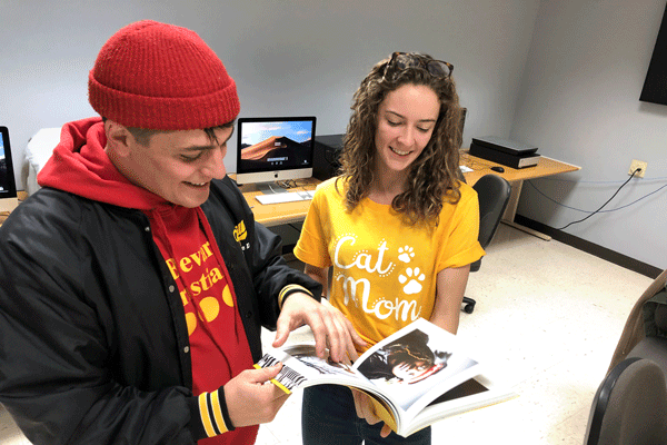 Two students look through design book together