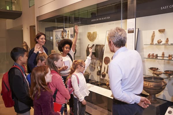 Museum guide leading a tour group of children