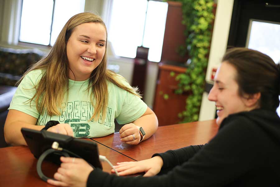 Student talking with housing front desk attendant in the Hendrickson Community Center