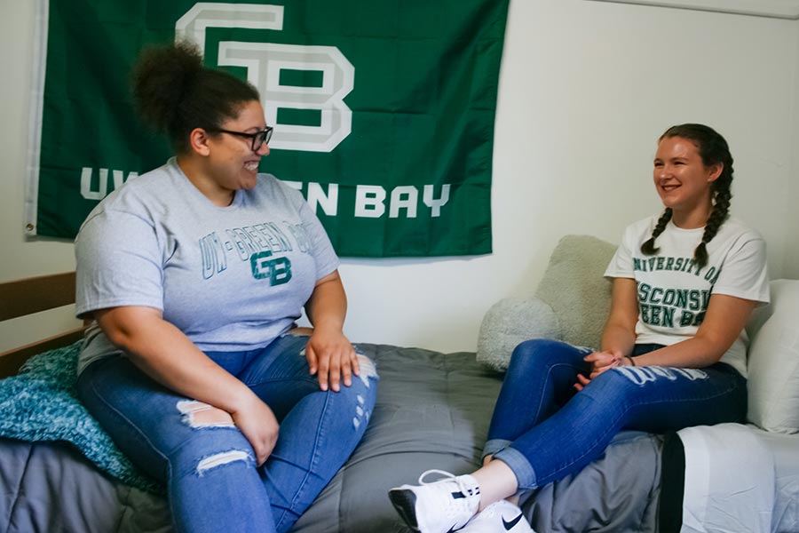 Roommates sitting on a bed in a UWGB dorm room