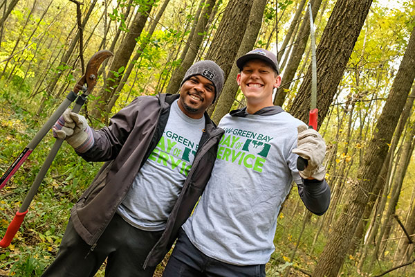 Two students doing brush clean up pose for photo during UW-Green Bay Service Day