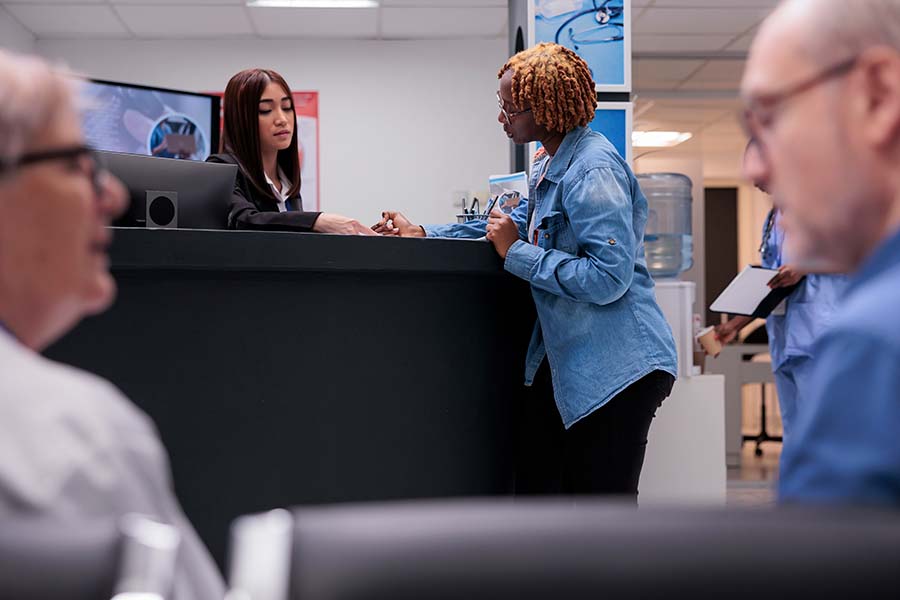 woman talking to receptionist completing paperwork