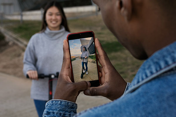 man recording vertical video on phone of a woman outside