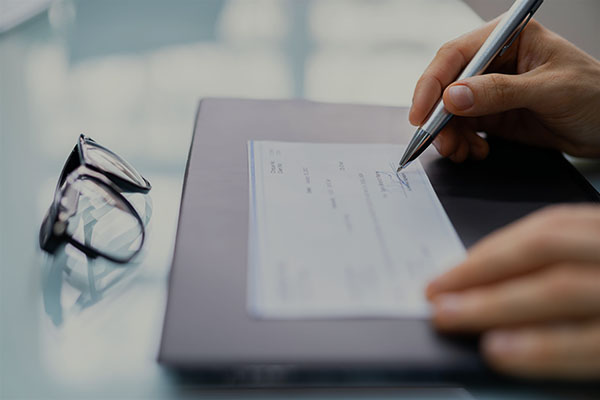 close up of person's hands writing a check