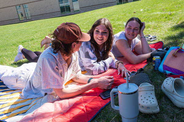 Three students hang out outside on campus