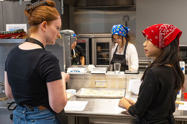 Dietetic students teach girl scouts cooking in kitchen