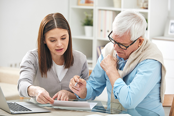 Young woman assisting older man with paperwork