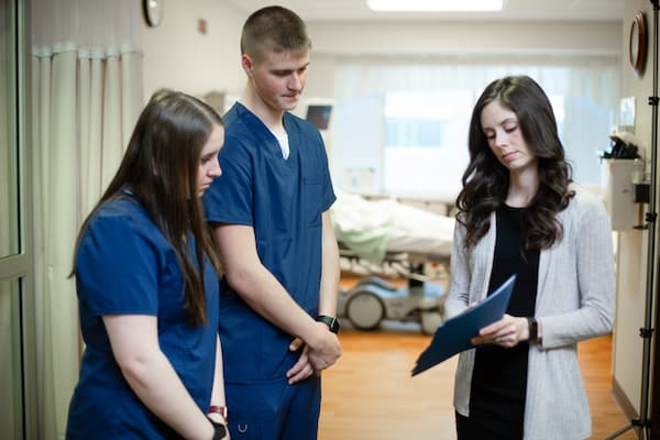 Students talk over documents with nurse