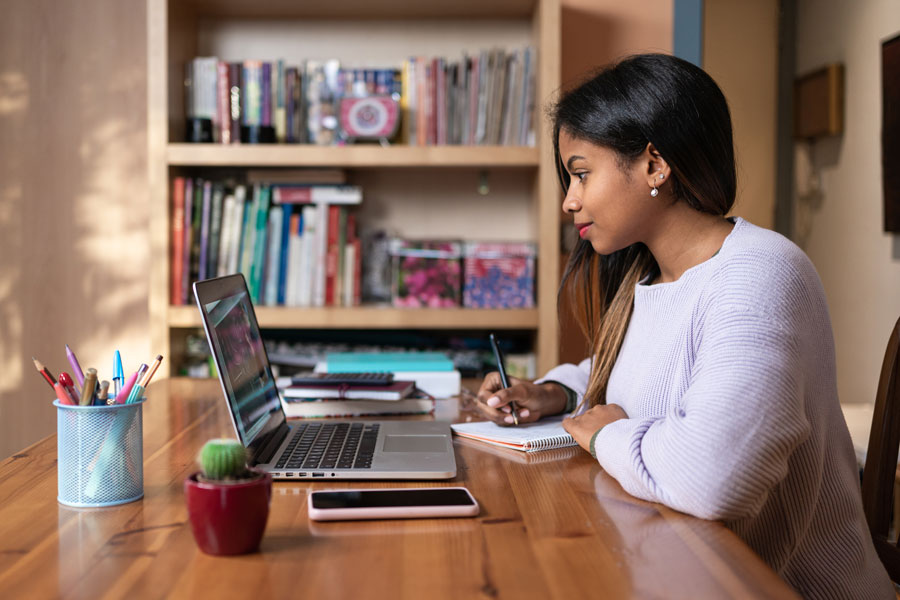 Woman taking notes at laptop