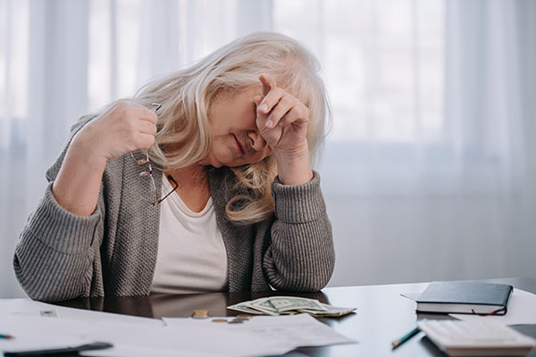 senior woman sitting at table stressed about finances