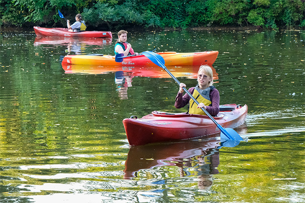 Students paddling kayaks in a uwgb pond