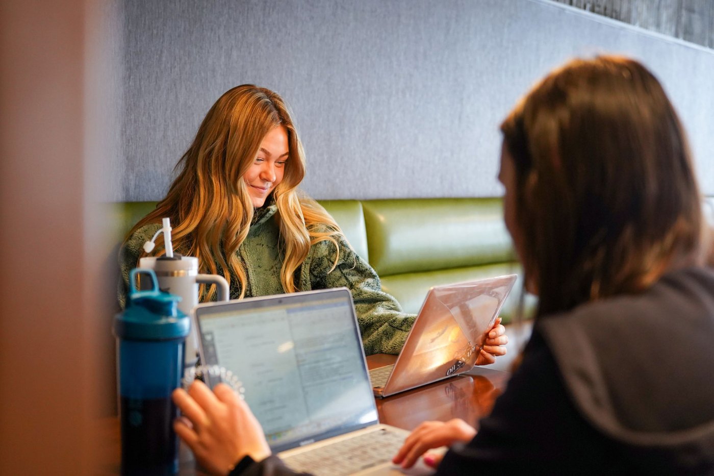 Two students study on laptops