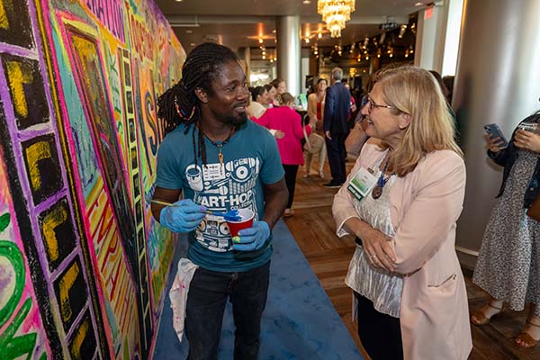 mural artist talking with women attending Celebrate 2024