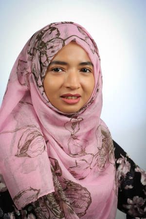 smiling person wearing a pink floral headscarf and black floral blouse