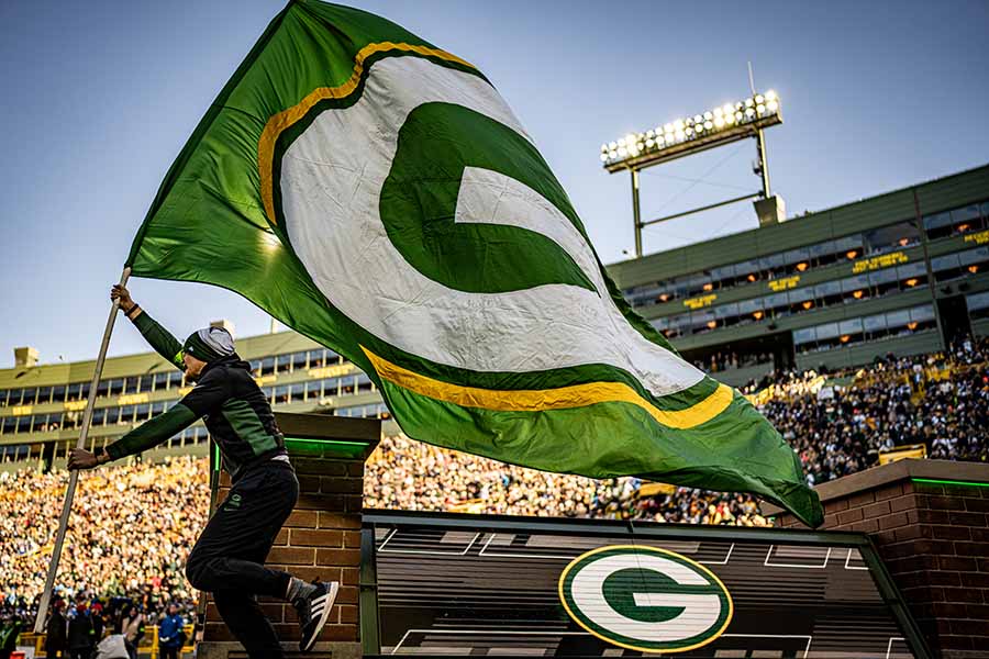 man running with Packers flag at Lambeau Field