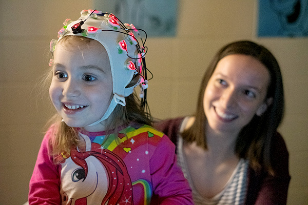 Researcher working with child in EEG cap