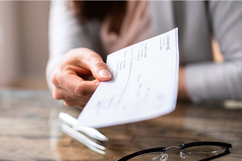 woman holding check out across desk