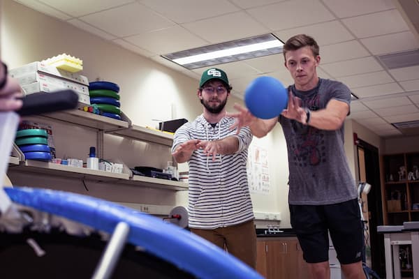 Student throws medicine ball at trampoline