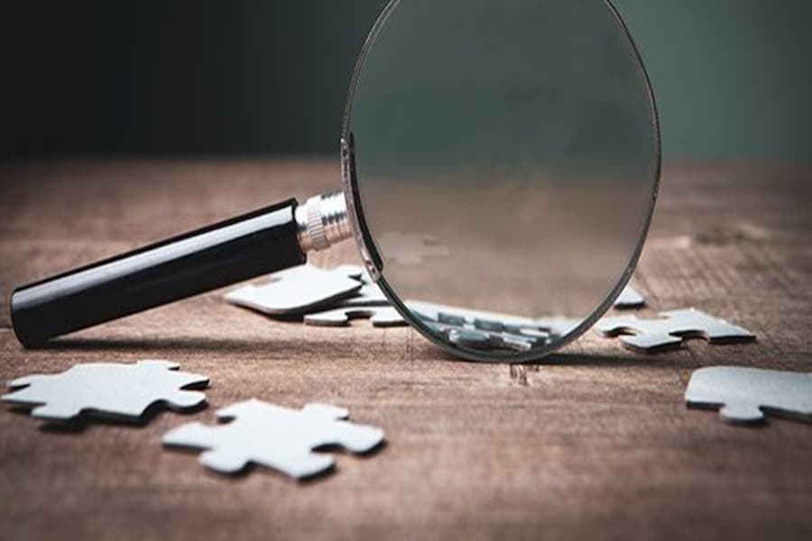 Magnifying glass and puzzle pieces on table