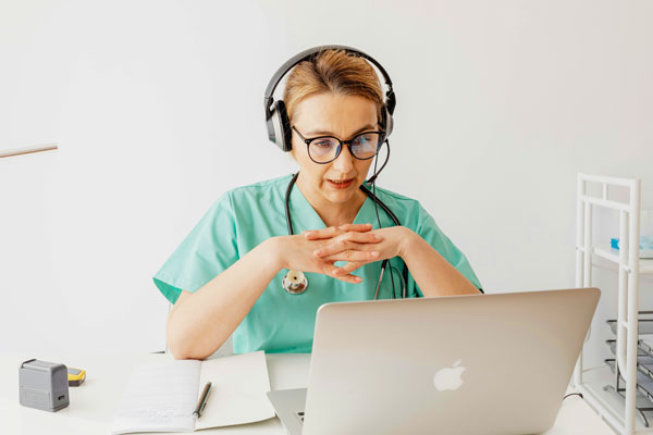 woman talking into headset & looking at laptop screen