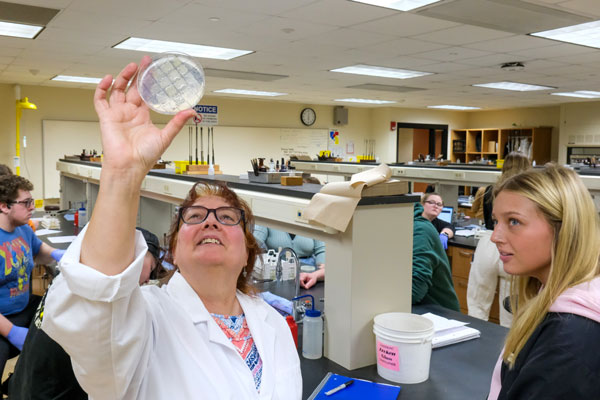 Professor holding up petri dish