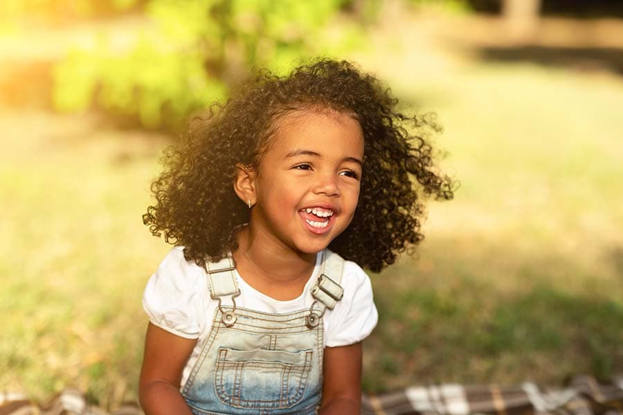 young child laughing sitting outside on the law