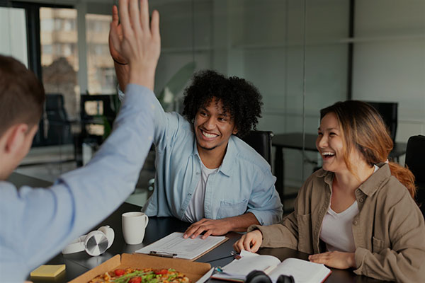 group of three happy employees high fiving during a meeting