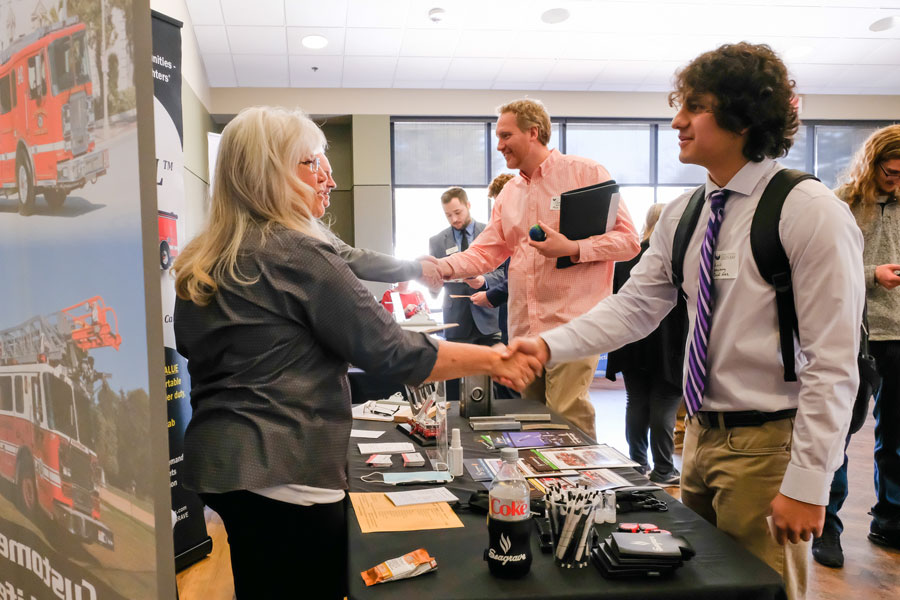Student shaking hands with woman at job and internship fair