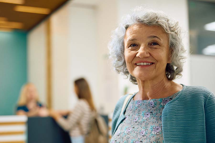 senior woman smiling near front desk of assisted living facility