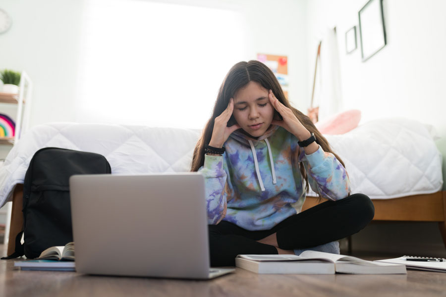 Stressed students with lap top and text books around her