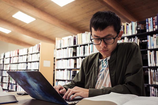 student working on laptop in library