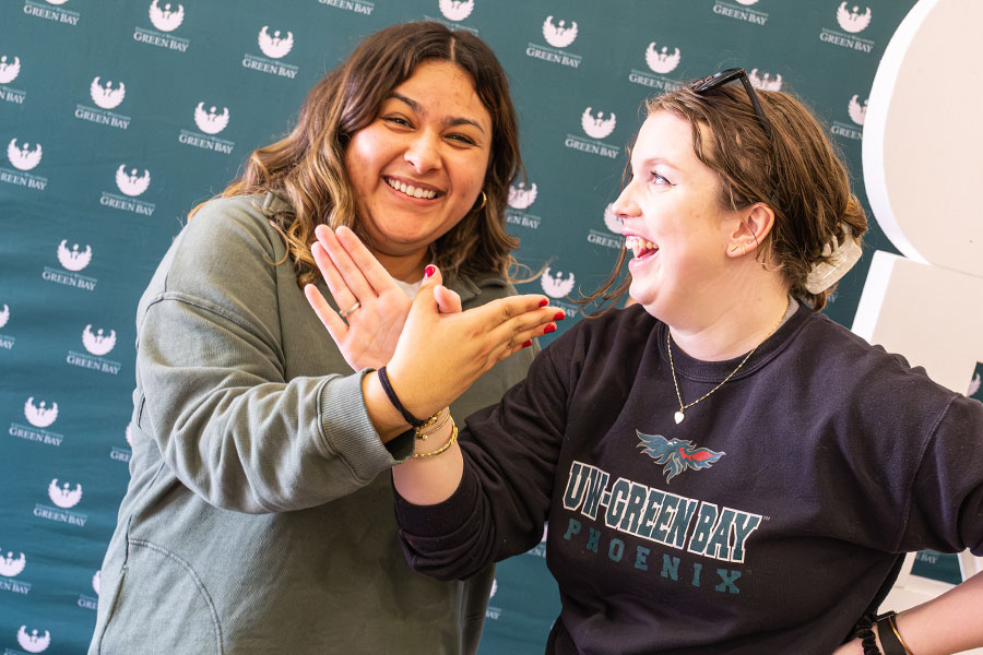 Laughing students each using a hand to form a phoenix gesture