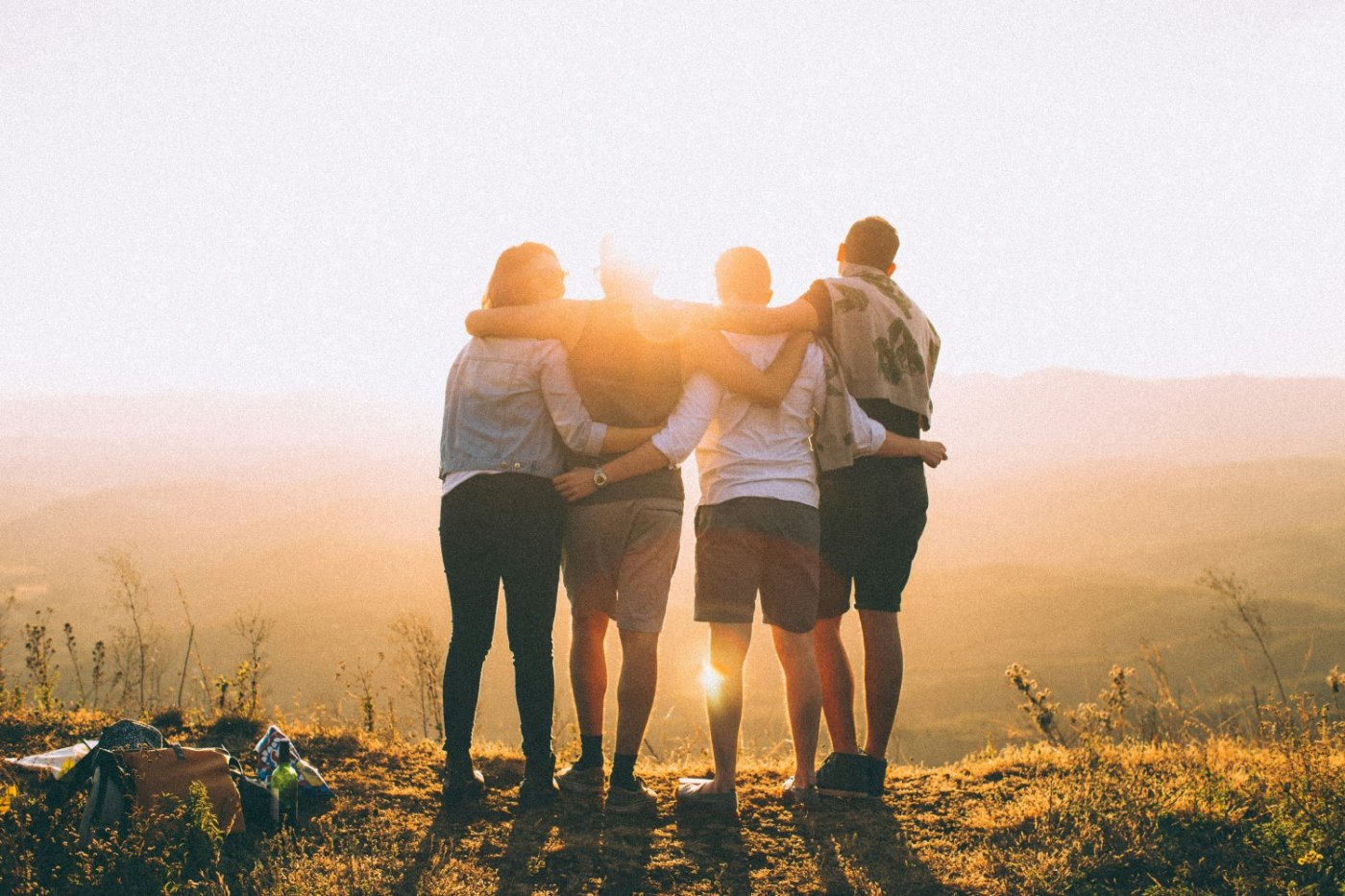 four friends looping arms at sunset