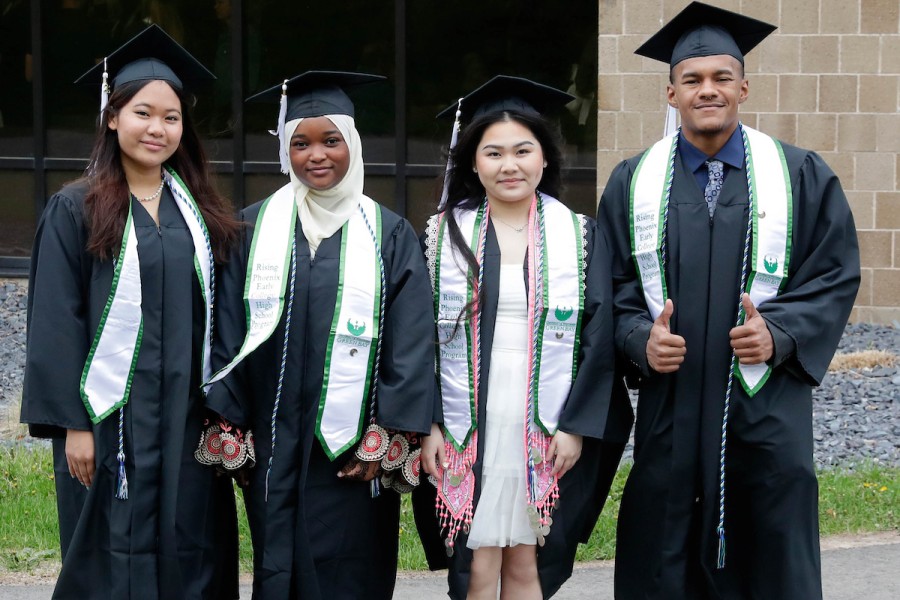 Four students standing together in graduation robes and hats