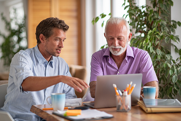 Young man working with a senior man on a laptop