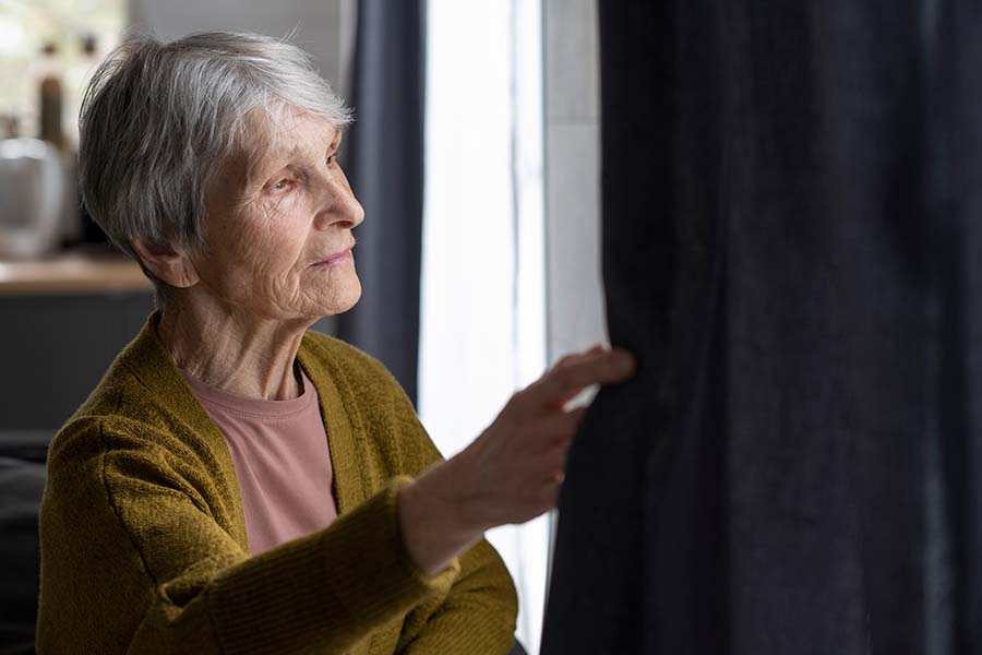 Elder person looking out a window