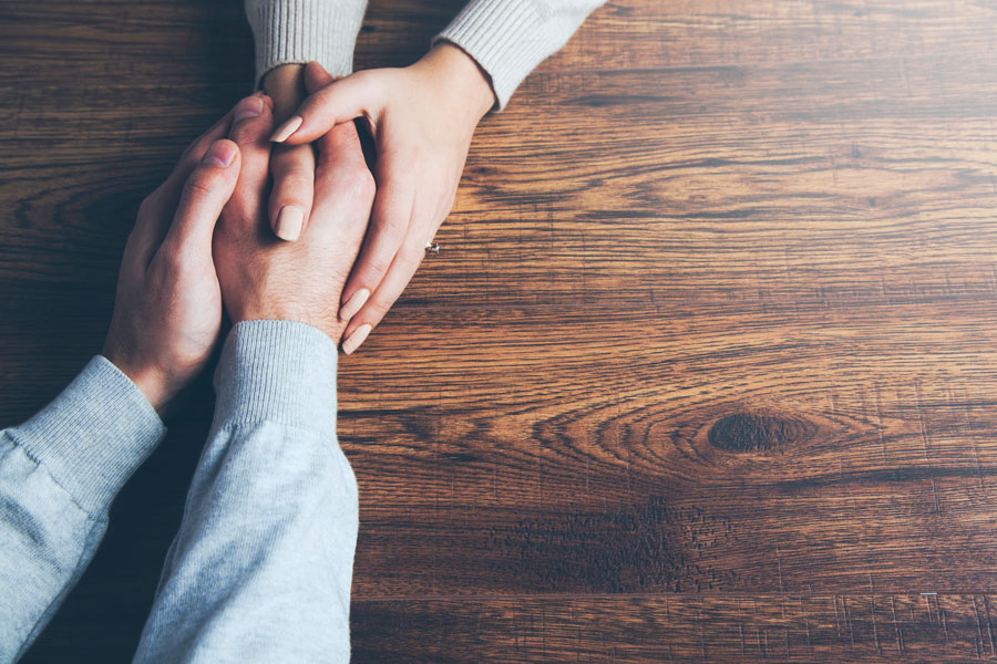 Two people holding hands in caring manner