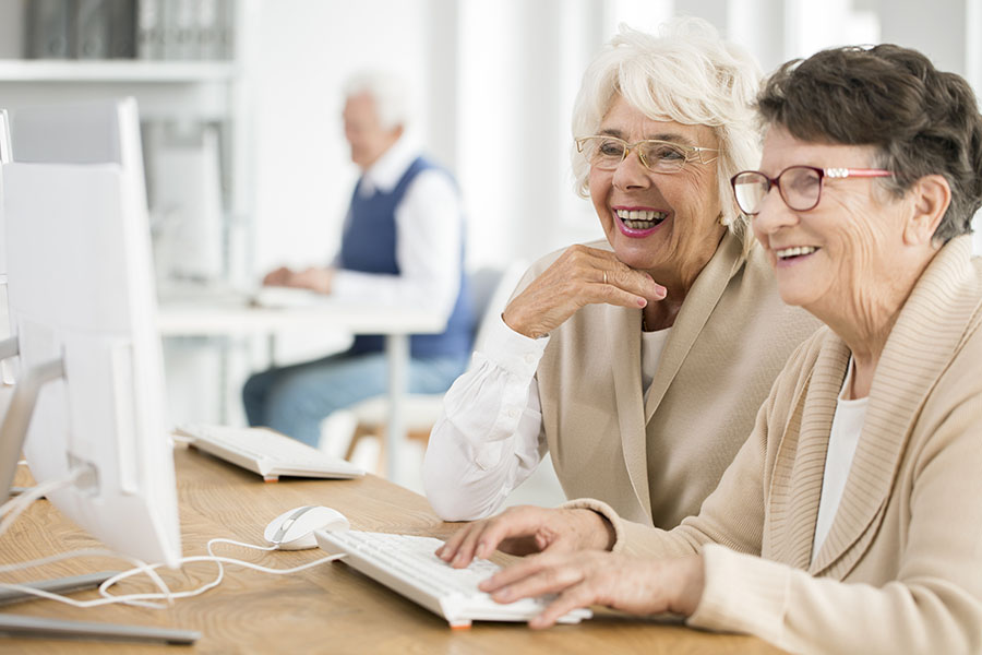 two senior women using a computer to watch an online class