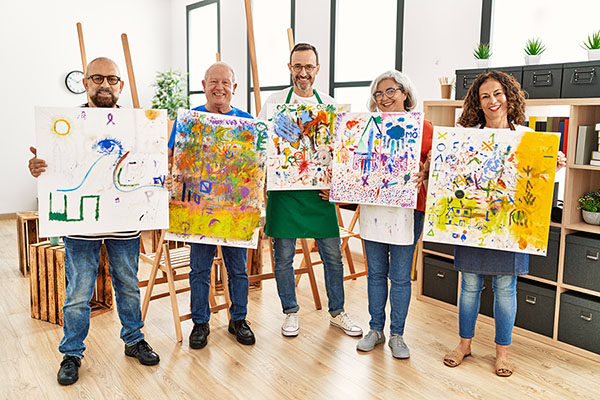 Group of adults showing off their paintings
