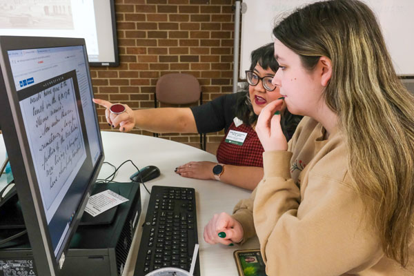 Two students at computer looking through archives