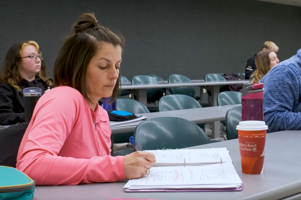 Graduate student taking notes during class